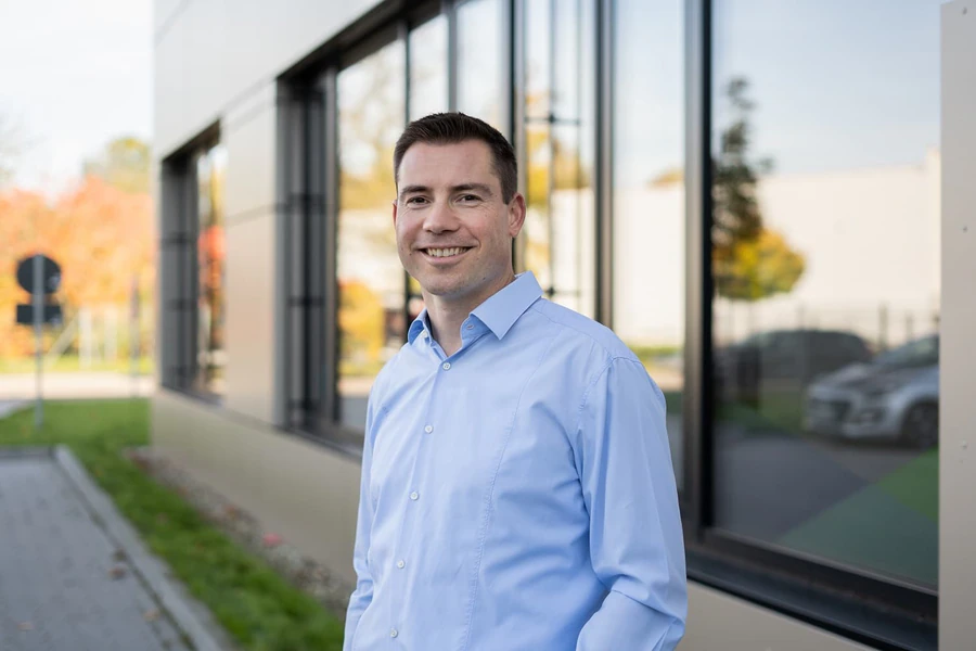 Daniel Büchle im hellblauen Hemd vor einem Bürogebäude