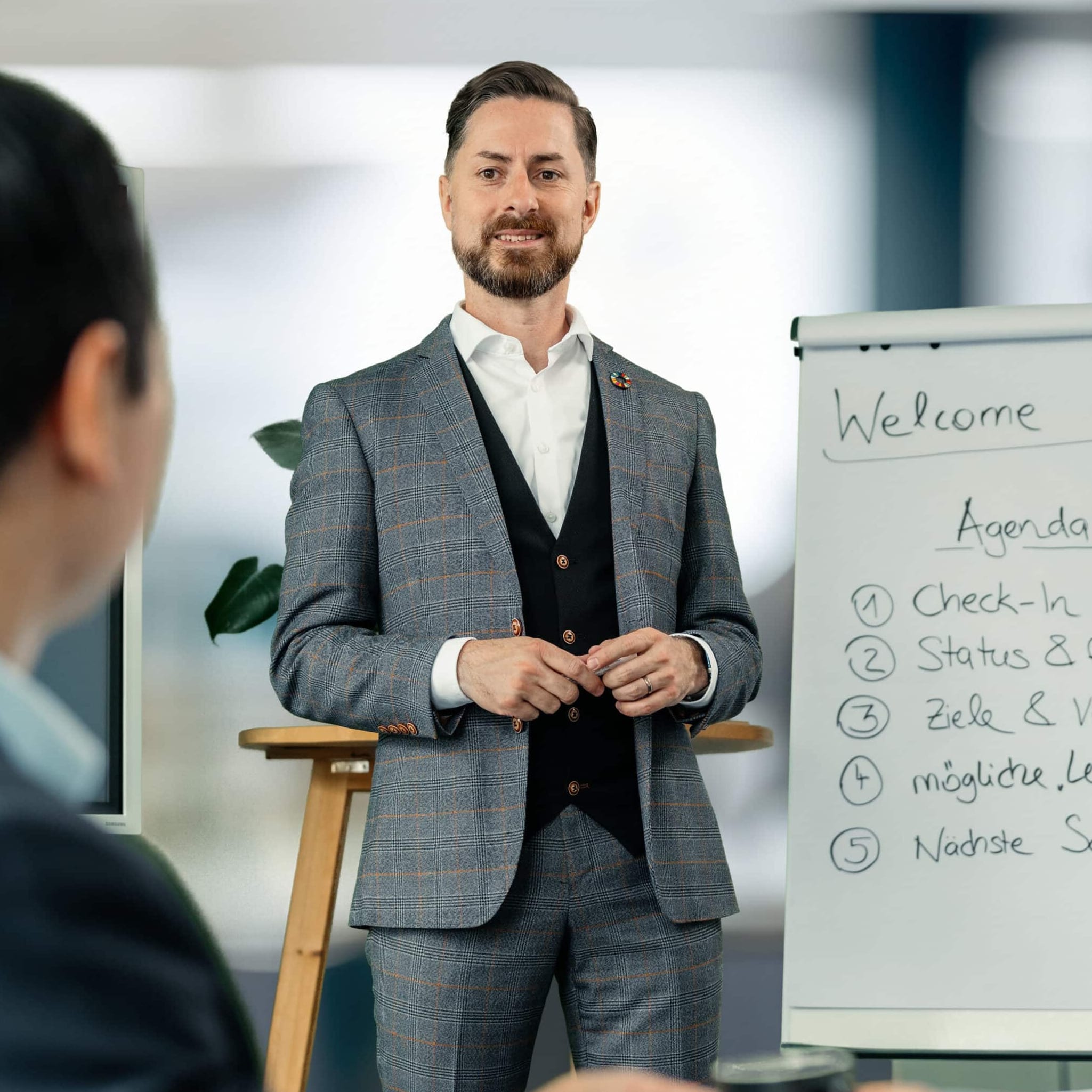 Rainer Karcher steht vor einem Flipchart, auf dem Welcome und Agenda steht