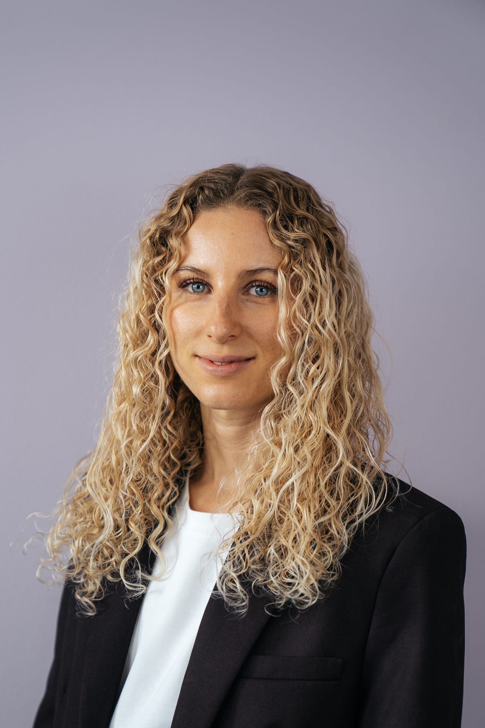 Porträt von Anthea Wagner im dunklen Blazer vor hellem Hintergrund