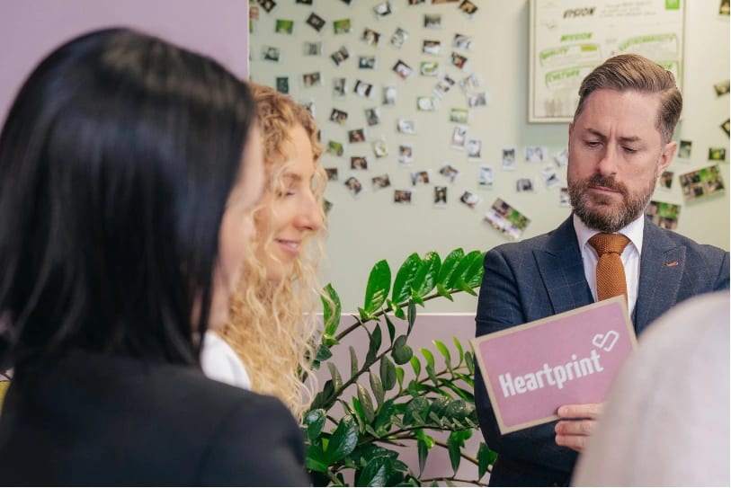 Das Heartprint-Team sitzt, Rainer Karcher blickt auf seine Moderationskarten.