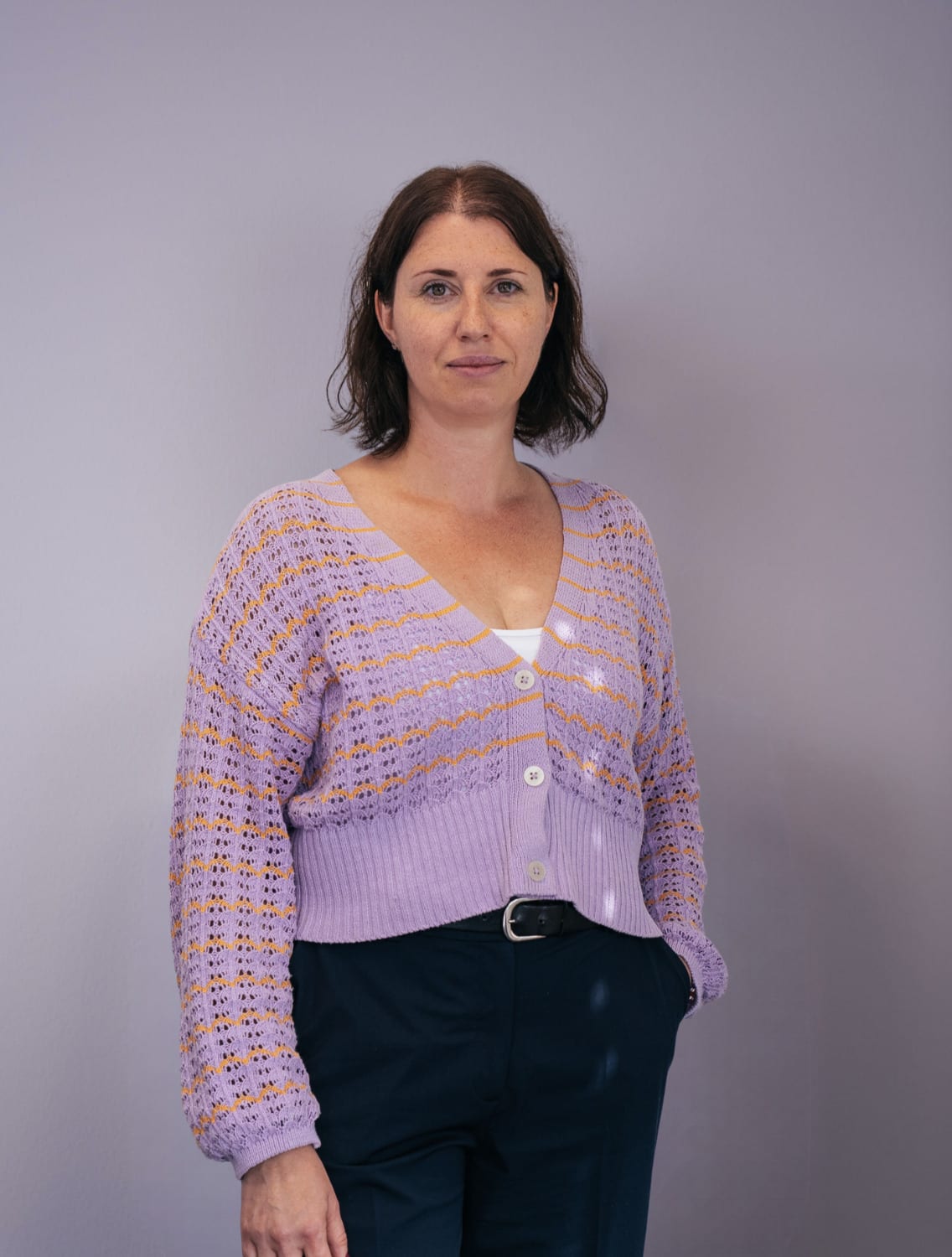 Porträt von Stefanie Karcher in lila Strickjacke vor hellem Hintergrund