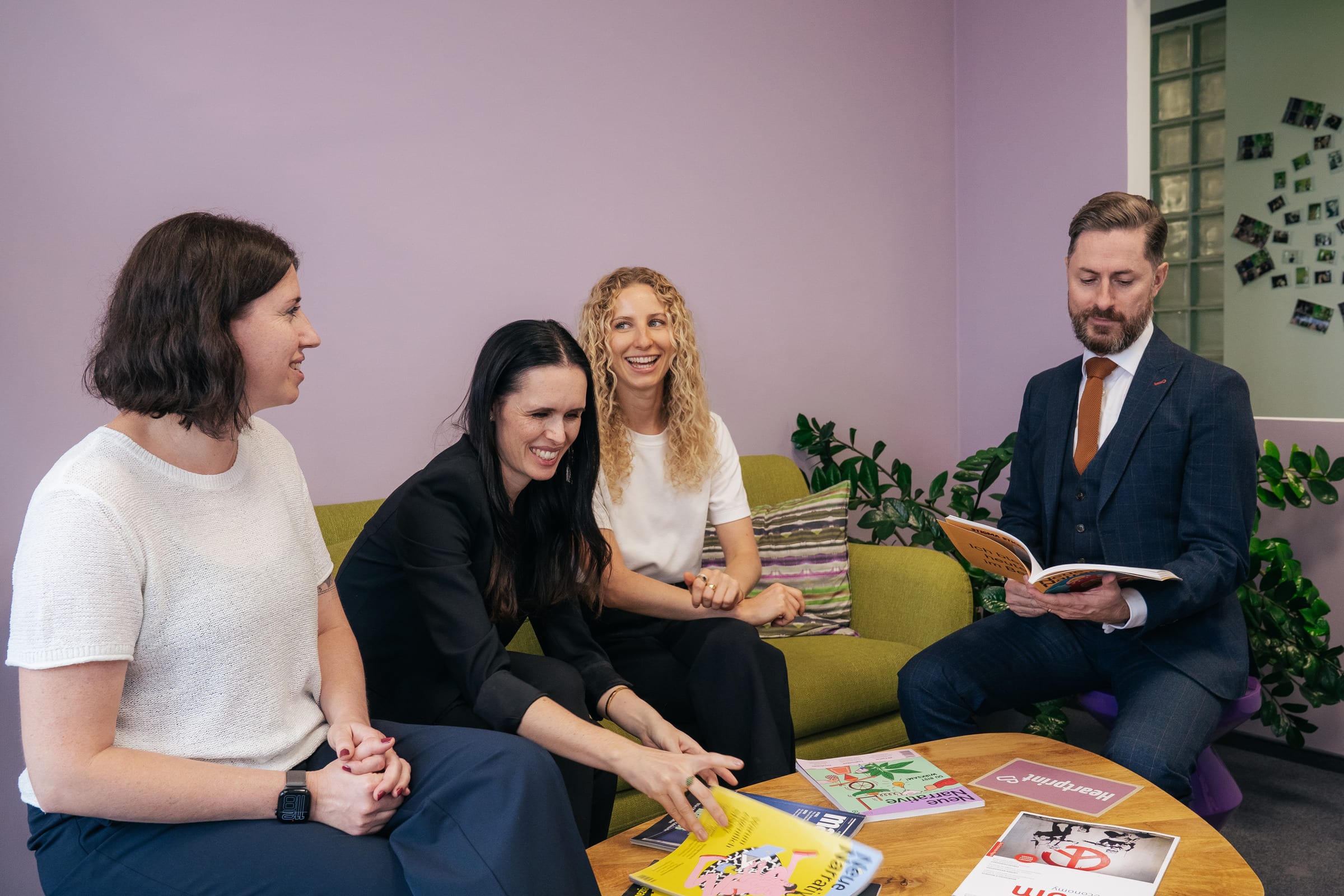 Stefanie Karcher, Jessica Ryan-Tietz, Anthea Wagner und Rainer Karcher sitzen um einen Tisch mit Zeitschriften und unterhalten sich gut gelaunt