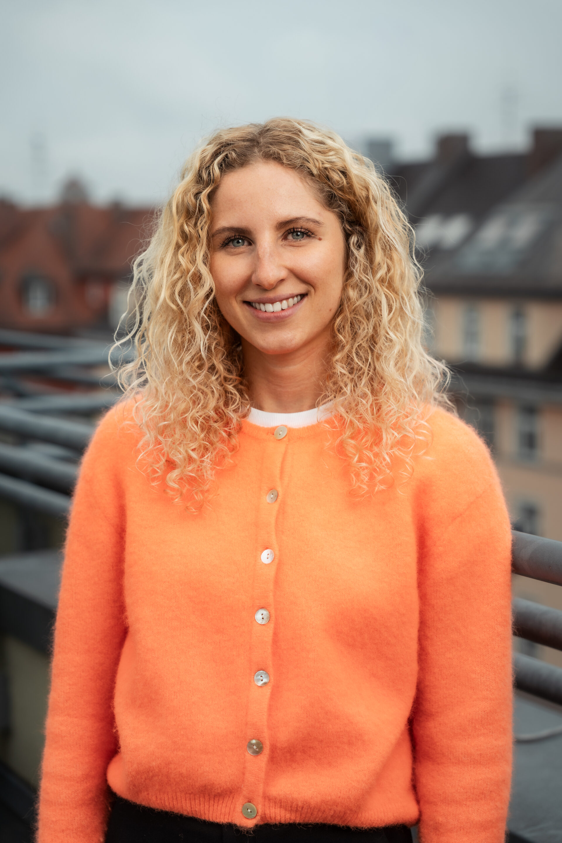 Porträt von Anthea Wagner, die mit orangefarbenem Oberteil im Freien steht